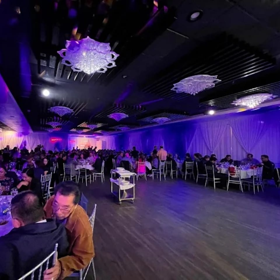 A large dining hall at Diamond Palace, filled with guests seated at tables under purple lighting and chandeliers.