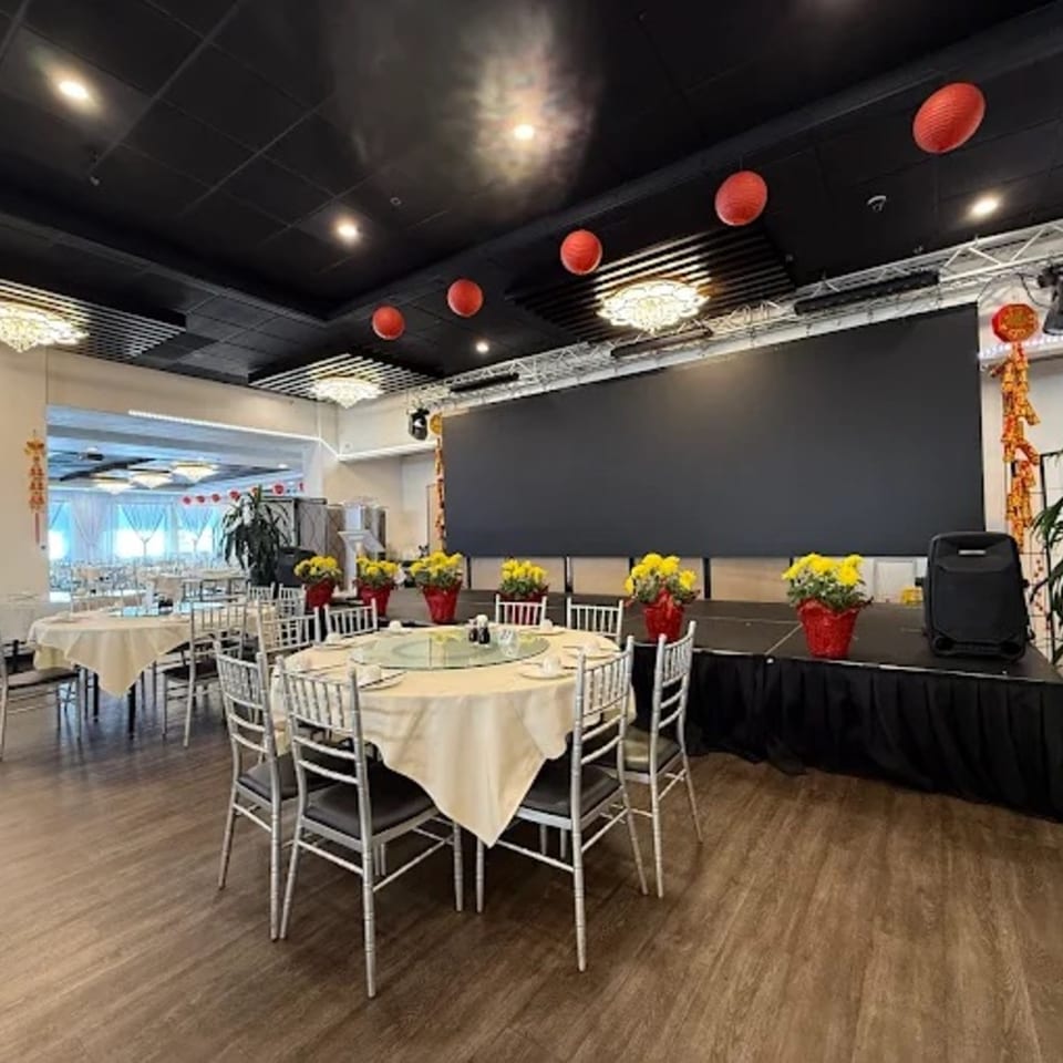 Diamond Palace dining room with round tables, silver chairs, red lanterns, and a large screen stage.