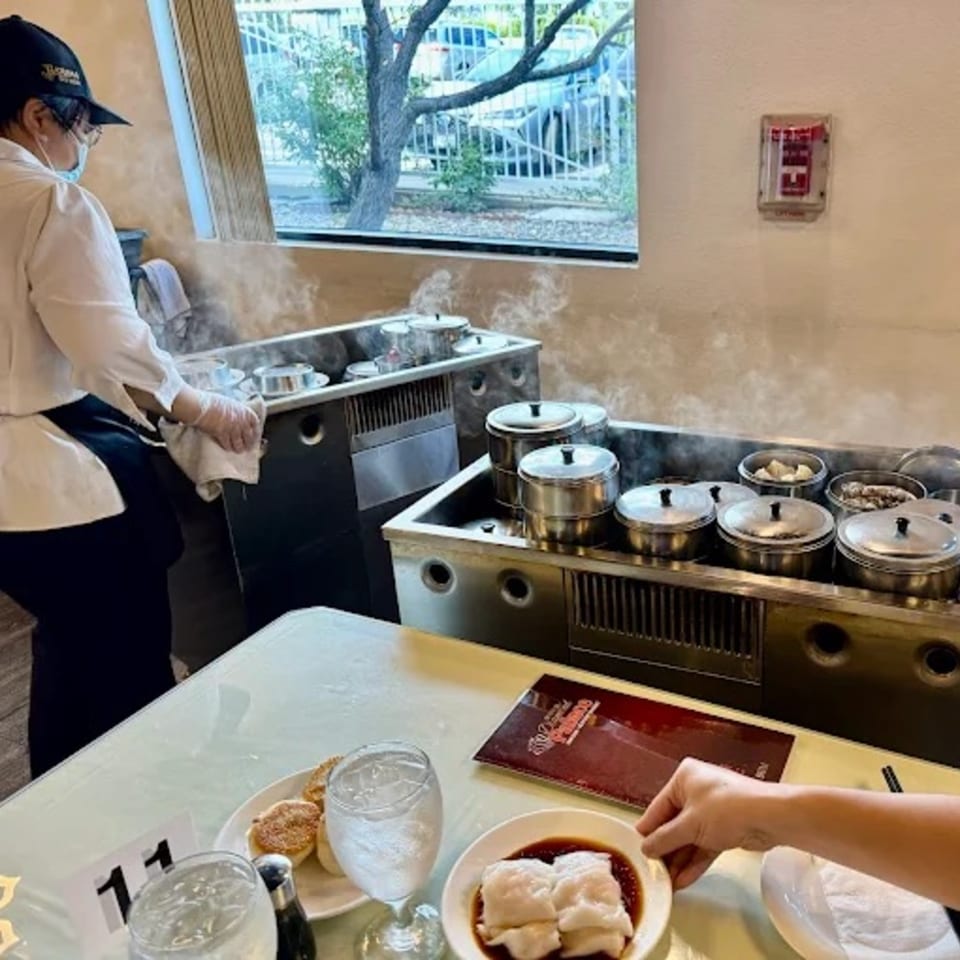 A server tends to steaming dim sum carts, while a customer enjoys rice rolls at Diamond Palace.