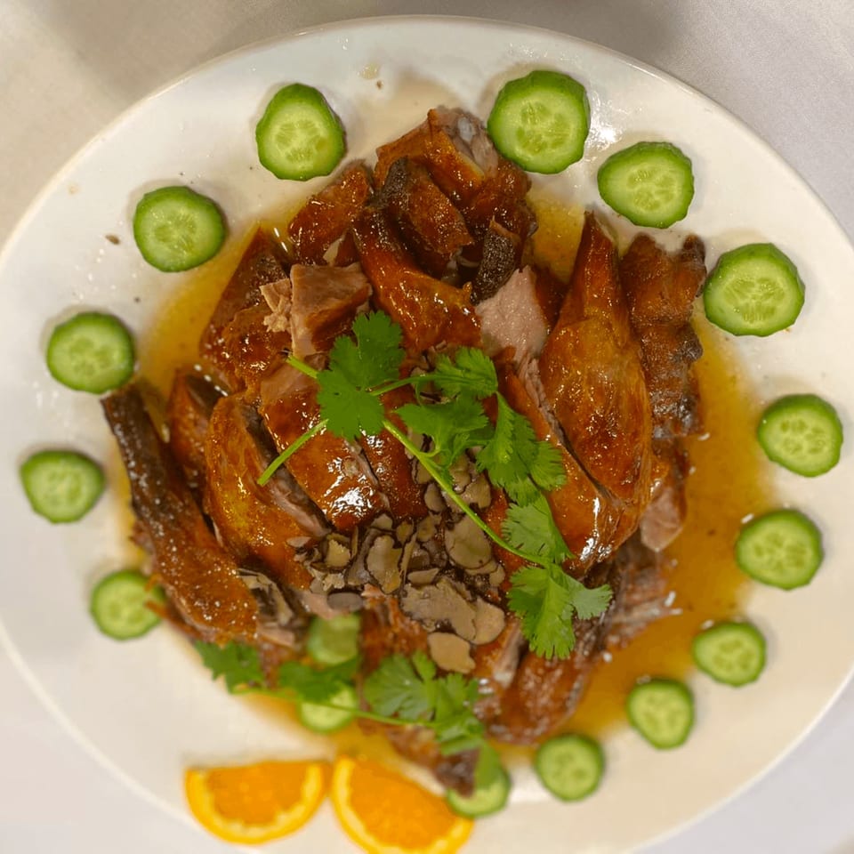 Diamond Palace's roasted duck, garnished with cucumber slices, cilantro, and orange wedges.