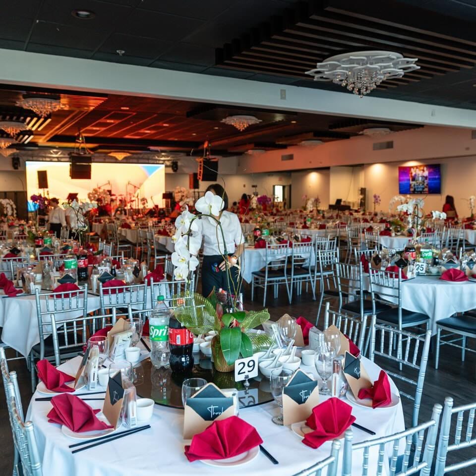 A large, elegant Diamond Palace dining room set with white tablecloths, red napkins, and silver chairs.